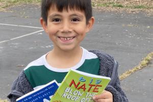 Boy from Made in Santa Rosa Education Foundation holding books