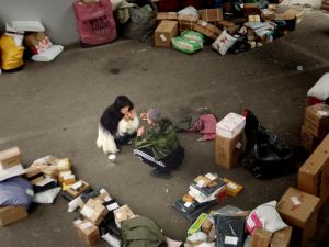 The lead characters of 'The Black Box' sitting among hundreds of undelivered packages in the streets of Shanghai, China, a powerful scene depicting the impact of the Covid-19 pandemic on their long-distance relationship.