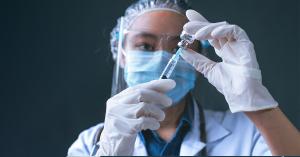 Medical professional in PPE is inserting a syringe into a vaccine bottle, as the FDA approved the first ever RSV vaccine