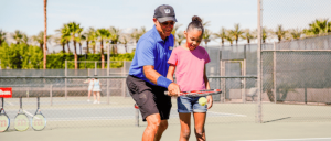 JW Marriott Desert Springs Resort & Spa  tennis instructor helping young African America girl with tennis skills